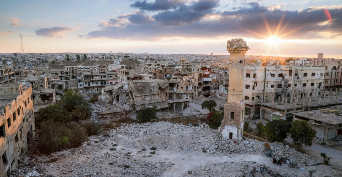 the sun is setting over the ruins of a city